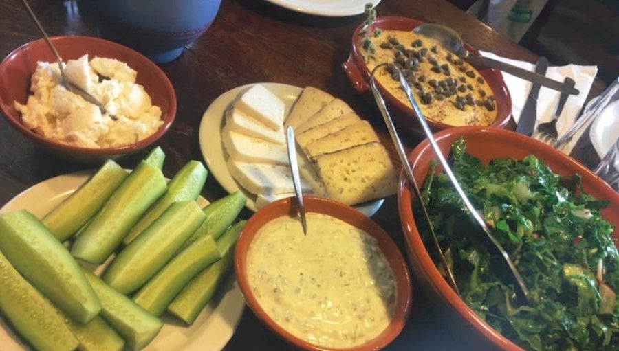 close-up of ceramic bowls with cheeses, cutted cucumbers, boiled herbs from 'Narlis Farm'